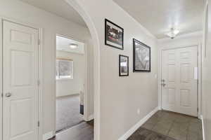 Entryway with arched walkways, a textured ceiling, and dark wood finished floors