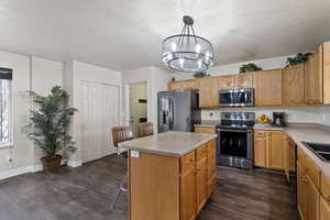 Kitchen with stainless steel appliances, a kitchen bar, light countertops, a kitchen island, and a textured ceiling