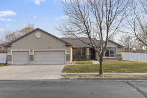 Ranch-style home with stone siding, stucco siding, a garage, and concrete driveway