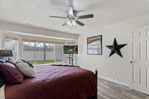 Bedroom featuring a textured ceiling, light wood-type flooring, and a ceiling fan