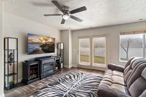 Living room featuring a textured ceiling, wood finished floors, healthy amount of natural light, and a ceiling fan