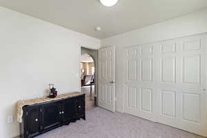 Bedroom with light carpet, arched walkways, a closet, and a textured ceiling