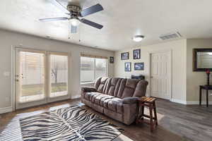 Living room featuring dark wood finished floors, a textured ceiling, and a ceiling fan