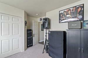Exercise area featuring a textured ceiling and light carpet