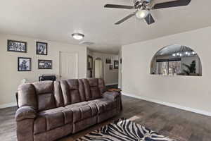 Living room featuring wood finished floors, arched walkways, and a ceiling fan