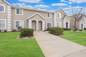 View of front of house with stucco siding and a front lawn
