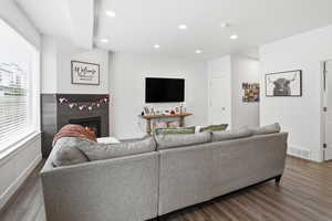 Living area with wood finished floors, a lit fireplace, and recessed lighting
