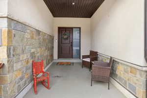 Entrance to property featuring stone siding, stucco siding, and a patio