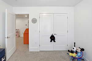 Unfurnished bedroom with light carpet and a closet