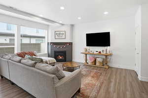Living area with a lit fireplace, recessed lighting, and wood finished floors