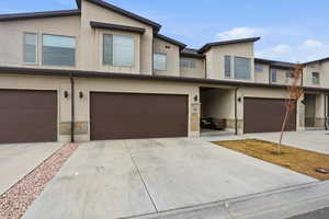Contemporary home with stone siding, stucco siding, and concrete driveway
