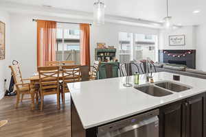 Kitchen with dark brown cabinets, dishwasher, a tile fireplace, dark wood finished floors, and healthy amount of natural light