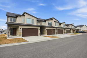 Modern home featuring stucco siding, driveway, stone siding, and a garage