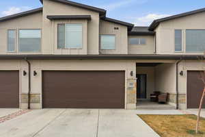 View of front of home featuring stone siding, covered porch, and stucco siding