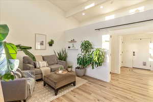 Living room with high vaulted ceiling, light wood-type flooring, and recessed lighting