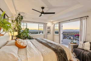 Bedroom with a ceiling fan, a raised ceiling, and a mountain view