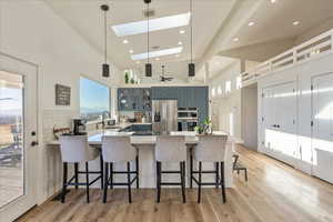 Kitchen with a peninsula, a kitchen bar, high vaulted ceiling, glass insert cabinets, and pendant lighting