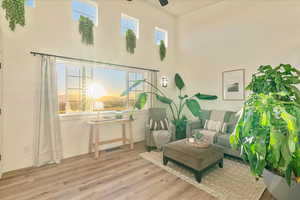 Living area featuring wood finished floors, ceiling fan, and a towering ceiling