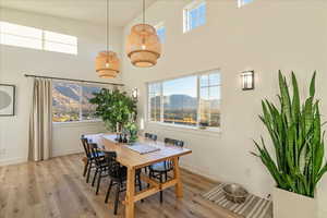 Dining area featuring light wood-style flooring, a towering ceiling, plenty of natural light, and a mountain view