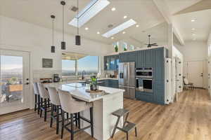 Kitchen featuring hanging light fixtures, a peninsula, a kitchen bar, stainless steel appliances, and high vaulted ceiling