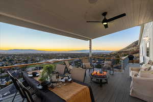Deck at dusk featuring a ceiling fan, a mountain view, a fire pit, and area for grilling