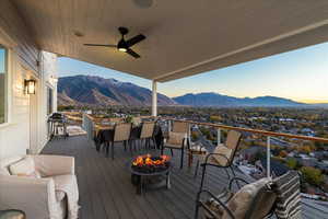 Wooden terrace with a mountain view, a ceiling fan, a grill, an outdoor fire pit, and outdoor dining area