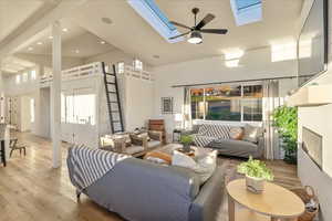 Living room featuring a high ceiling, hardwood / wood-style floors, ceiling fan, recessed lighting, and a skylight