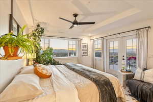 Bedroom with french doors, multiple windows, a ceiling fan, and a raised ceiling