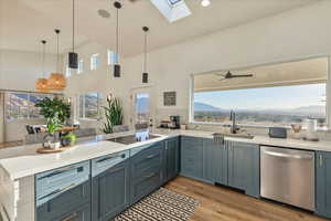 Kitchen with a skylight, light wood-style flooring, dishwasher, a peninsula, and pendant lighting