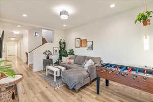 Living area with light wood finished floors, recessed lighting, and stairs