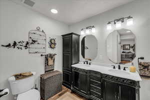 Ensuite bathroom featuring double vanity and light wood-style floors