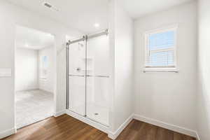 **DISCLAIMER** Interior color package may vary.Bathroom featuring a shower stall and dark wood-style flooring