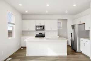 **DISCLAIMER** Interior color package may vary.Kitchen featuring white cabinets, stainless steel appliances, recessed lighting, a center island with sink, and dark wood-style floors