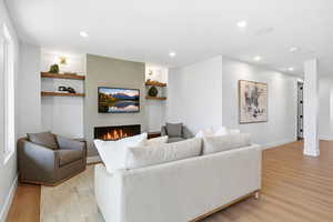 Living room with light wood finished floors, recessed lighting, and a fireplace
