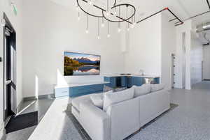 Living area with a towering ceiling, speckled floor, a chandelier, and beverage cooler