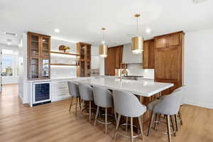 Kitchen with open shelves, glass insert cabinets, brown cabinets, a kitchen bar, and light stone counters