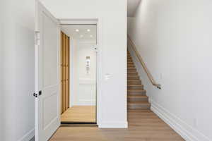 Stairway with wood finished floors, elevator, and recessed lighting