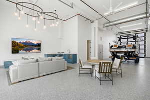 Dining room with a high ceiling, speckled floor, a ceiling fan, and a chandelier