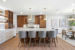 Kitchen with glass insert cabinets, brown cabinetry, open shelves, light stone countertops, and recessed lighting