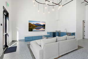 Living room featuring a high ceiling, dark aggregate flooring, and wine cooler