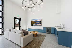Living area featuring wine cooler, a high ceiling, and a chandelier