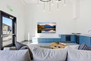 Living room featuring beverage cooler, dark speckled floor, and a towering ceiling