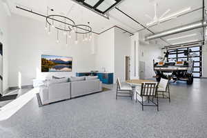 Dining space featuring a towering ceiling, speckle patterned floor, a chandelier, and a ceiling fan
