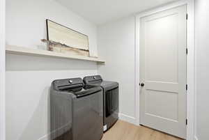 Laundry area featuring light wood-style flooring and washing machine and clothes dryer
