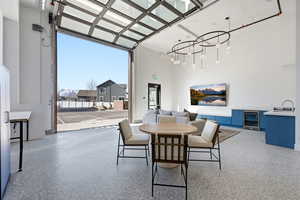 Dining room with a chandelier, dark speckled floor, wine cooler, and a high ceiling