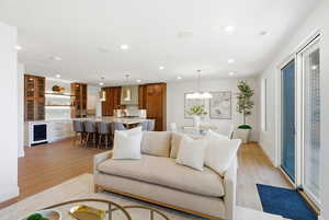 Living area with beverage cooler, light wood finished floors, and recessed lighting