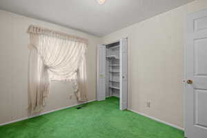 Unfurnished bedroom with wallpapered walls, a textured ceiling, carpet, and a closet