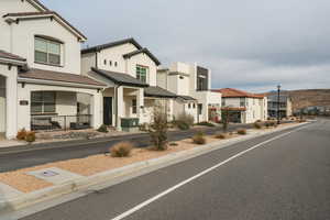 View of asphalt road with a residential view, street lighting, and curbs