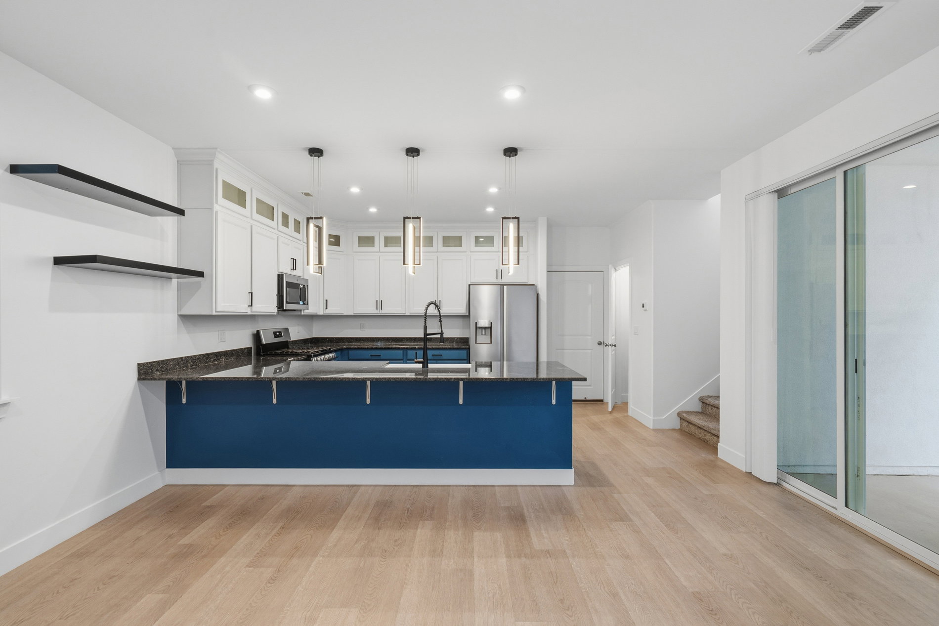 Kitchen featuring a peninsula, white cabinets, glass insert cabinets, a kitchen breakfast bar, and hanging light fixtures