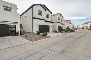View of front of house with a residential view, stucco siding, concrete driveway, and an attached garage